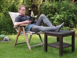 Mann in grauer Srumpfhose sitzt im Garten