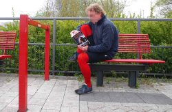 Ein Mann sitzt in einer roten Strumpfhose auf einer Bank