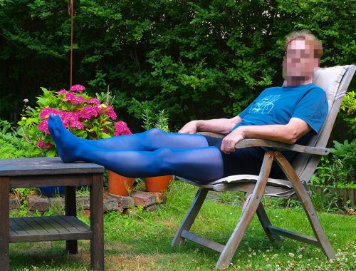 Mann sitzt in blauer Strumpfhose im Garten